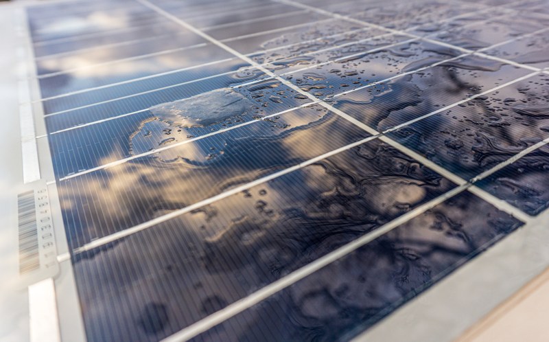 Picture of water droplets on a solar rooftop panel with a blurred vertical barcode visible on the left side.