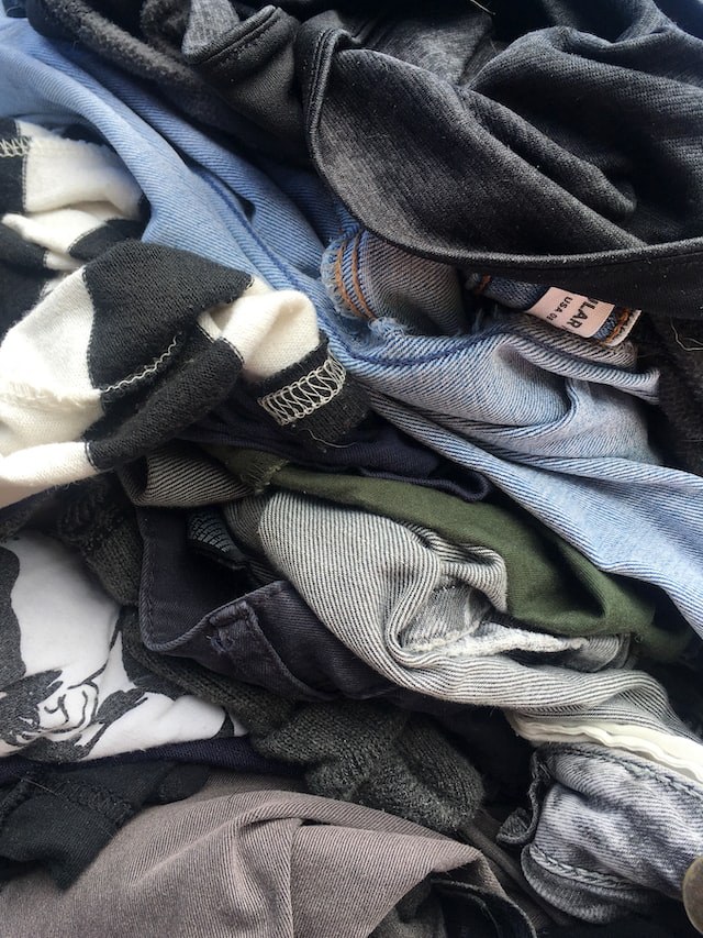 Picture of a close-up of different clothes, such as jeans, and tee-shirts, with part of a label visible on the top right.